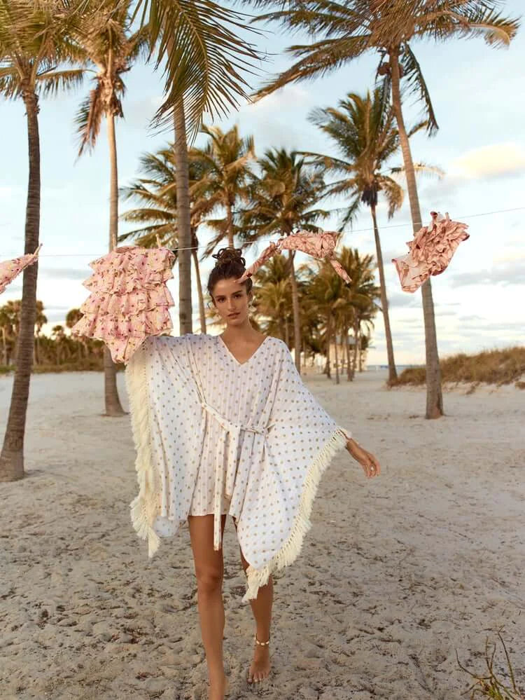 a model in a white fringe beach cover-up dress