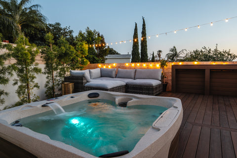 Hot tub with blue interior lighting in a nice backyard at dusk