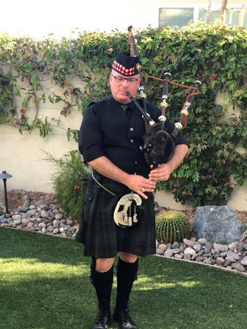 man playing bagpipes in a backyard