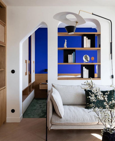 White room with arch leading to a room with blue walls and wooden details.