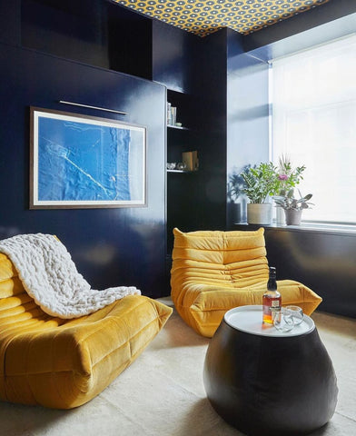 Room with dark blue walls and yellow lounge chairs.