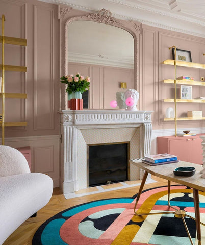 Dusty pink room with large mirror over fireplace and modern accessories.