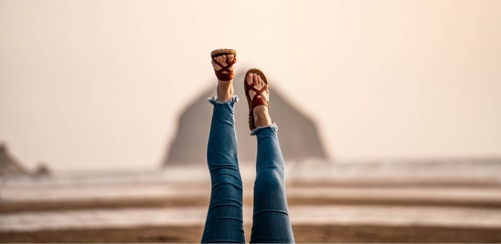 A woman wearing Acorn Everywear sandals at a beach