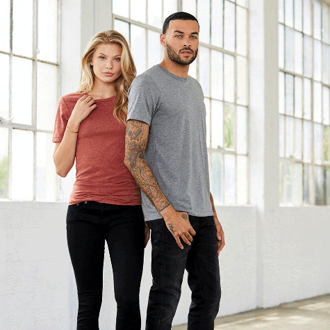 A woman and a man in custom Bella + Canvas custom t-shirts and black pants standing in a white room with windows