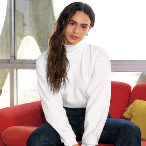 A woman in a white corporate American Apparel unisex sweater sitting on a red couch