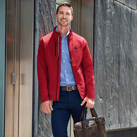 man leaning on wall wearing a red corporate Elevate men's jacket from Merchology