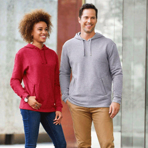 A woman in a red custom Next Level Apparel unisex hoodie and a man in a gray corporate Next Level Apparel unisex sweatshirt standing in front of a business