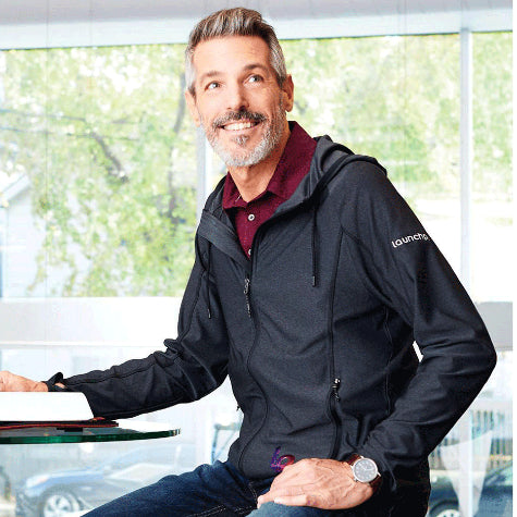 man at a desk wearing a corporate Elevate men's zip-up jacket