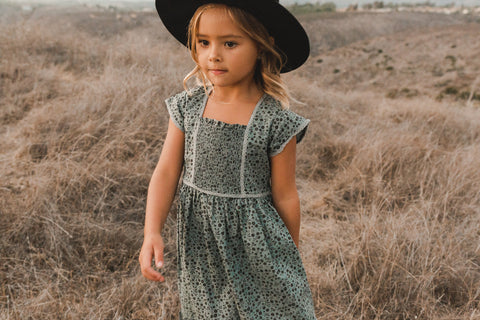 Little girl standing in a field wearing a felt hat and the new Madeline dress in Indigo Meadow from the Rylee + Cru AW21 Drop 2 collection