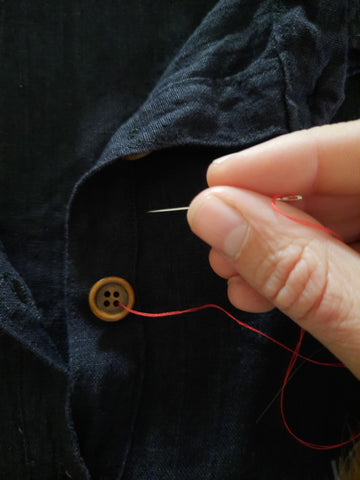 Threading the needle from underside of fabric through a buttonhole