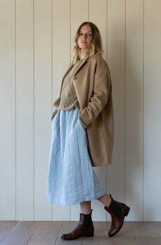 Model wearing Pyne & Smith linen dress with sweater, wool coat and boots