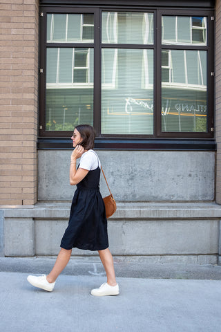 Seasons and Salt's Andrea wearing a Pyne & Smith No. 34 dress in black linen over a white tee with white sneakers