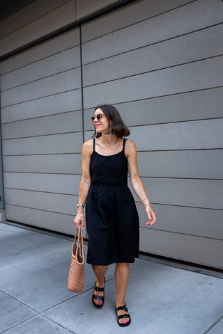 Seasons and Salt's Andrea wearing Pyne & Smith No. 34 dress in black linen with black sandals and a tan leather tote