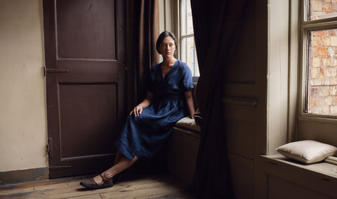 A Woman wearing a navy blue linen dress in a Georgian room