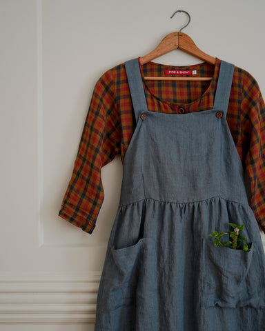 Pinafore dress layered over a checked long sleeve linen dress