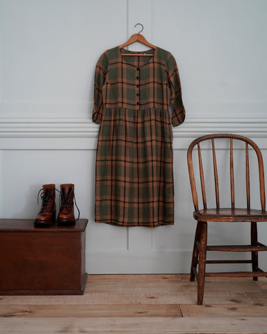 a scene of a hanging plaid linen dress and some lace up boots serves as style inspiration for pride and prejudice outfits