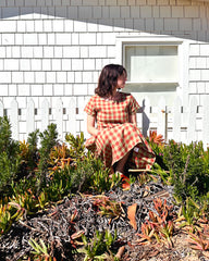 model in dress sits by fence 