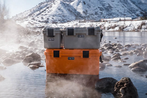 2 Yeti GoBox's sitting in the river in the winter-time.