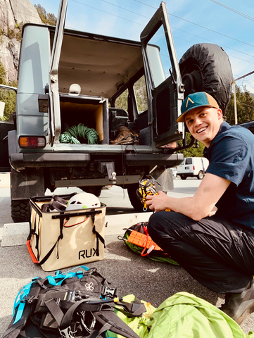 Man smiling next to his car, unloading his gear from the RUX 70L.