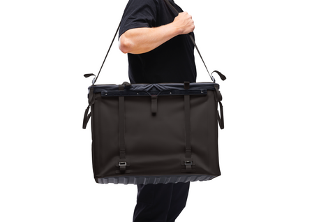 Studio shot of many holding RUX 70L with strap over shoulder to carry.
