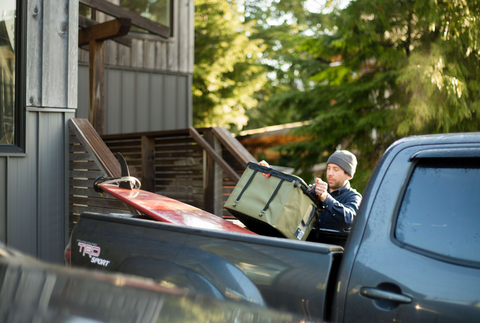 Man loading his packed RUX 70L into the back of his truck, ready for a trip.