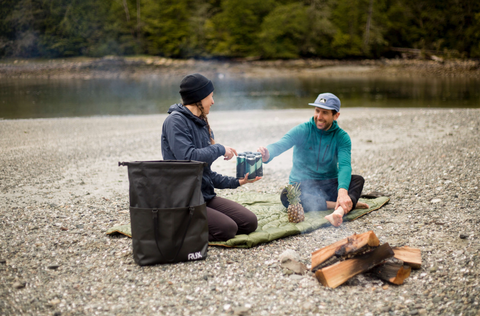 Two friends on the beach with their RUX Bag, sharing the food they brought.