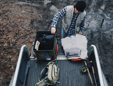 Aerial view of the RUX 70L, man unloading the bag from the trunk of his car, holding all of his fishing gear.