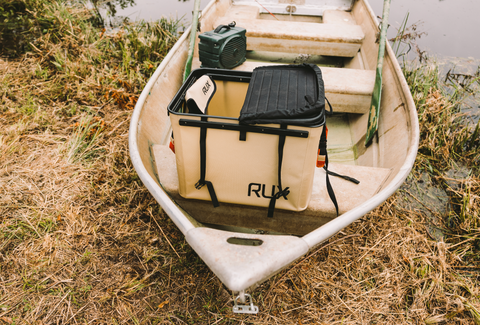 Boat on the shore, showing a close up of the RUX 70L and the wide-open mouth allowing for ample amount of storage.