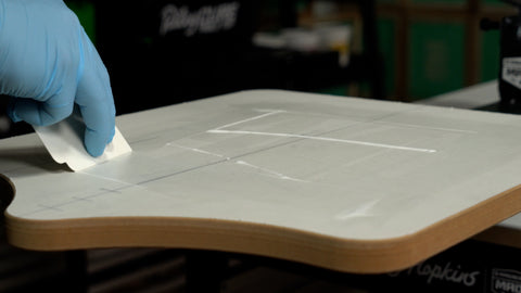 hand using a cleanup card to spread adhesive across a platen