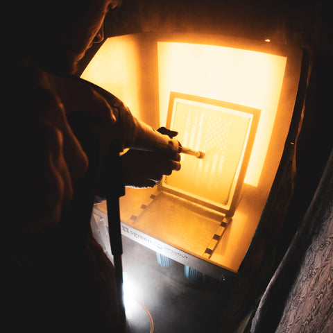 printer rinsing out a screen with a pressure washer in a washout booth