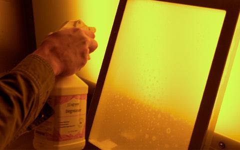 hand spraying a screen with degreaser