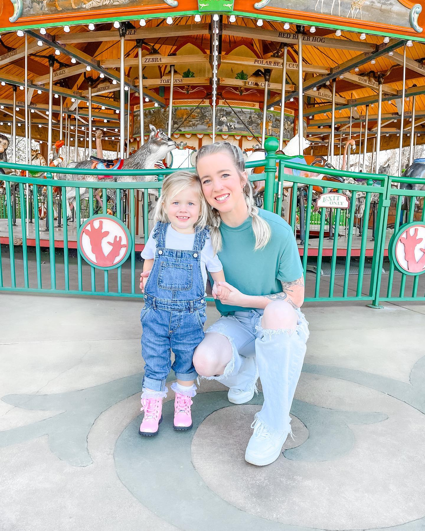 Brooke Hall with her daughter posing in front of the carousel at Nashville Zoo