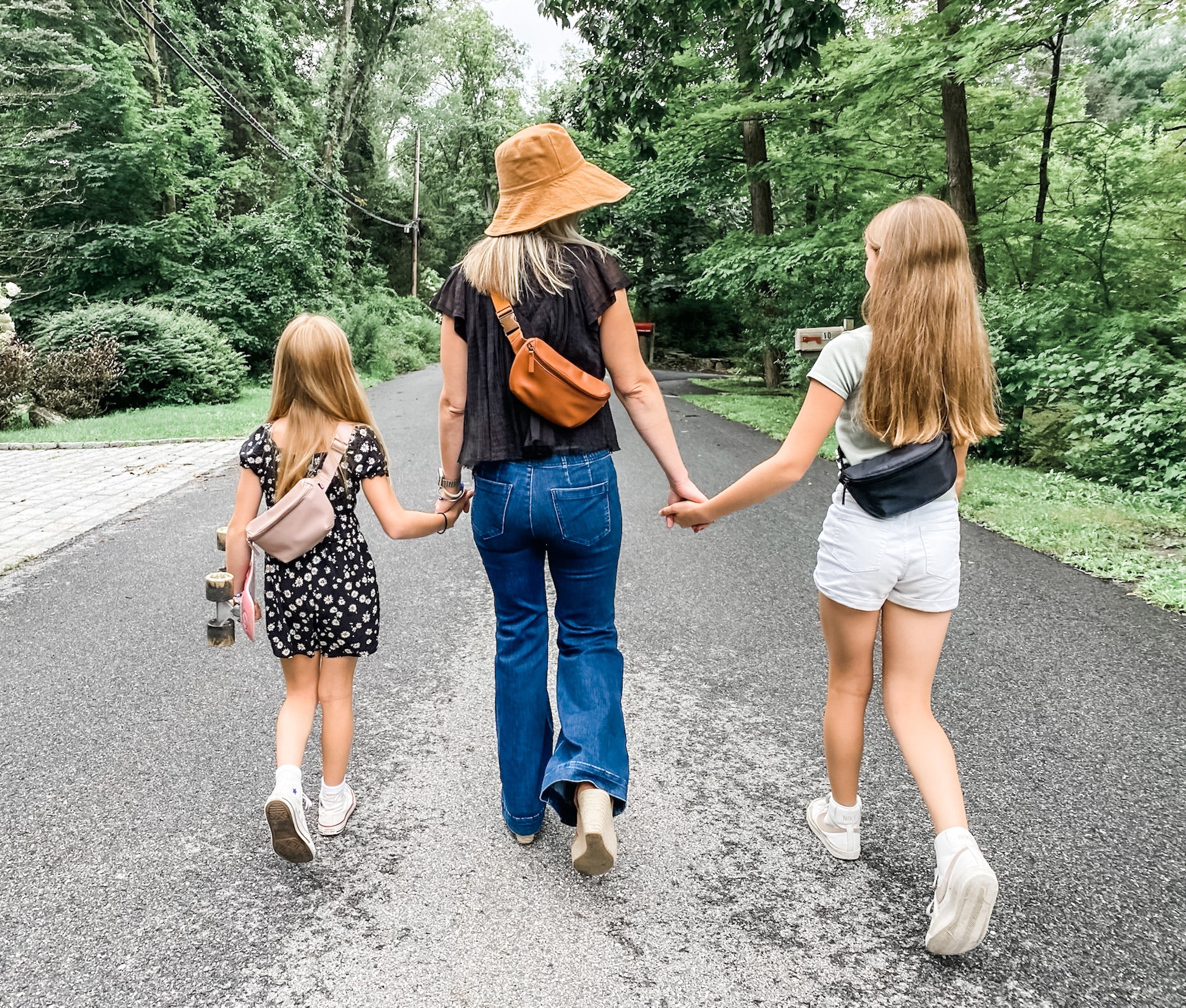 Mom and daughters on a walk in the country holding hands and all wearing Kibou Mini fanny packs