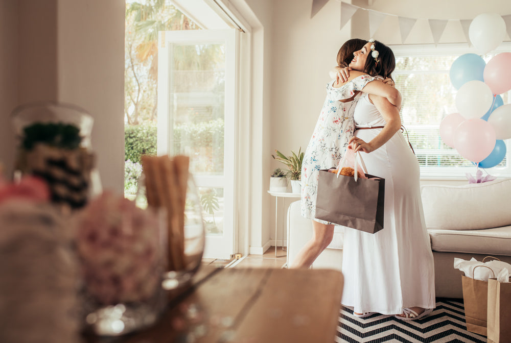 minimalist mom-to-be hugging friend in home at baby shower