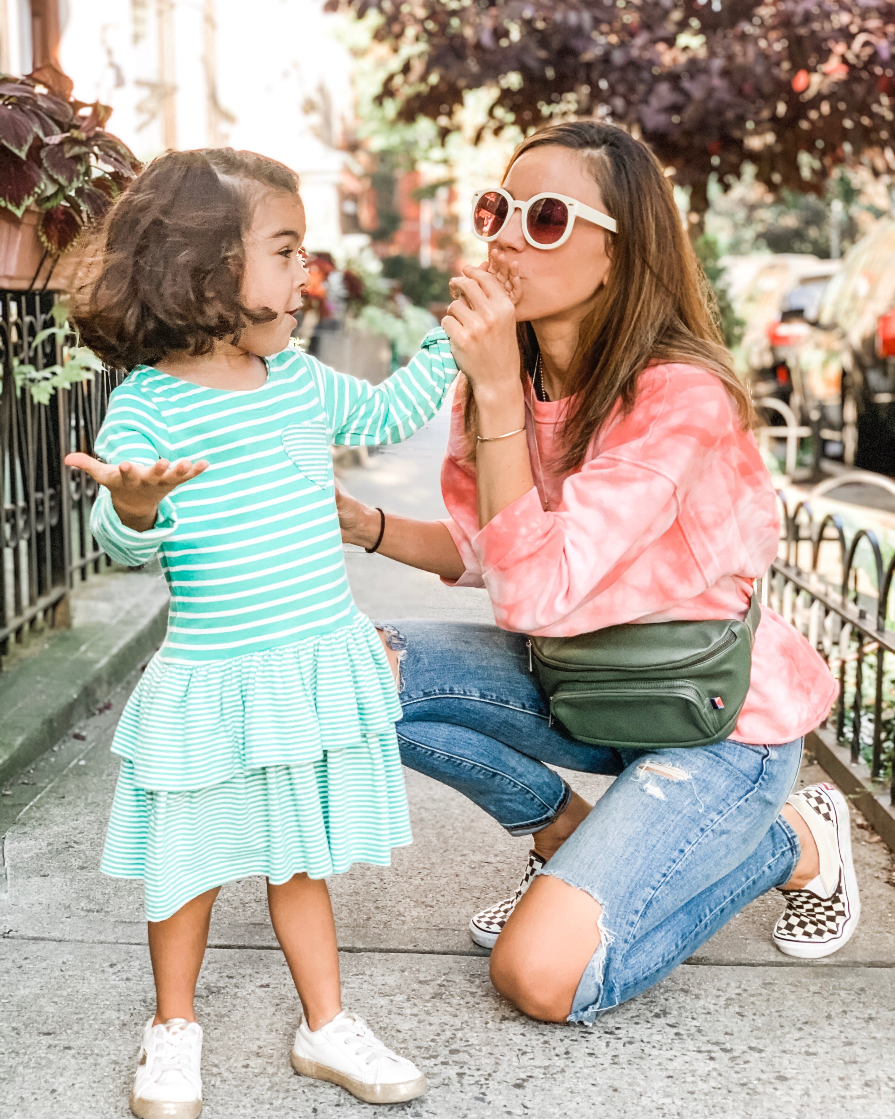 Woman kissing girl's hand wearing a toddler diaper bag