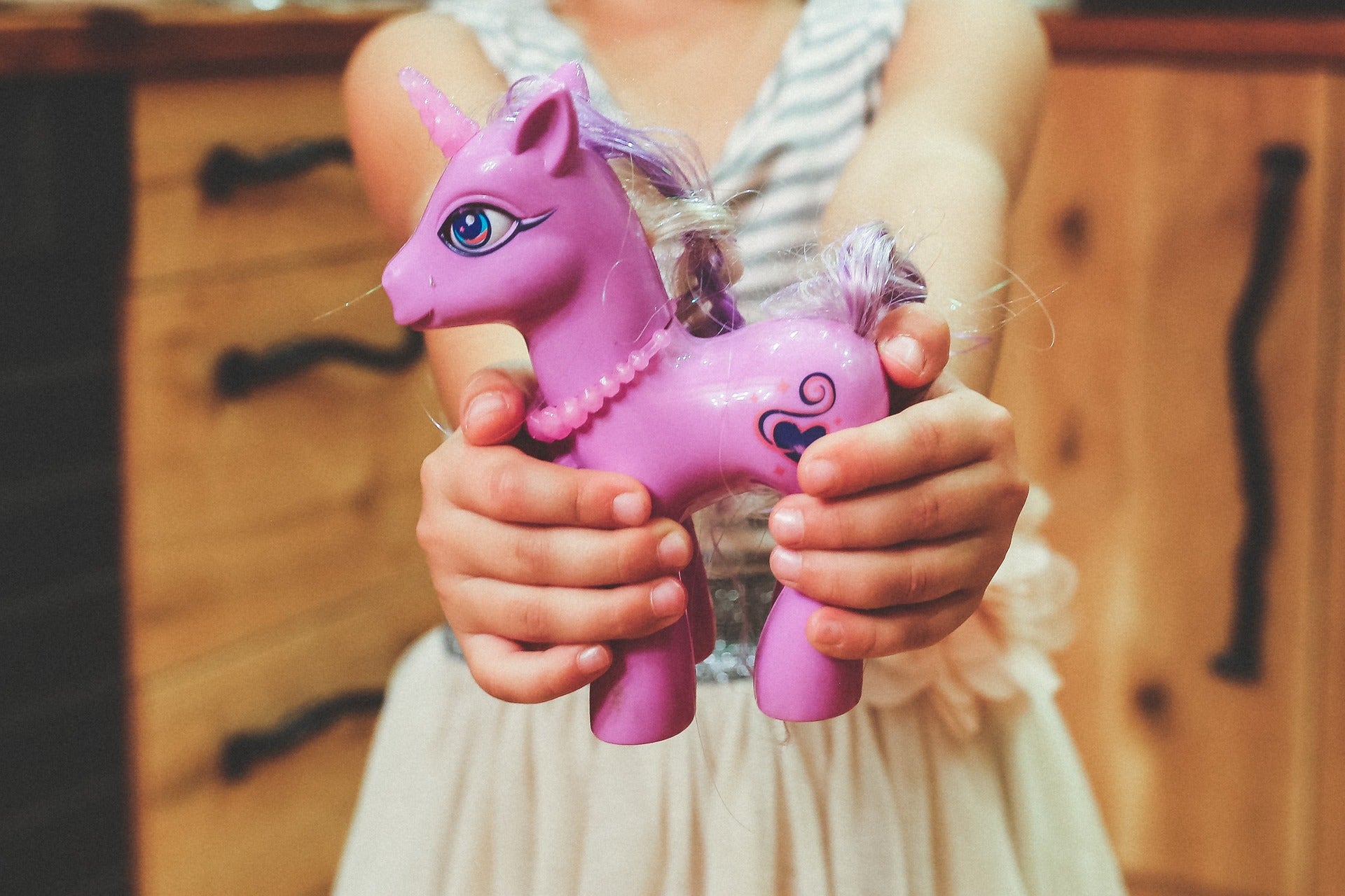 little girl holding purple pony toy