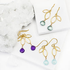 image of three gold leaf earrings with gemstones on white