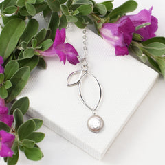 silver open leaf pendant with pearl on white background with flowers