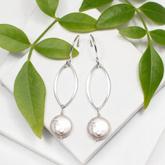 silver open leaf dangle earrings with coin pearls on white background with green leaf accent