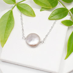 dainty coin pearl necklace on white background