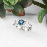 silver cactus skeleton pattern solitaire ring with center gemstone on white blocks with succulent in background