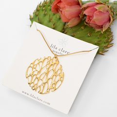 image of gold round cactus pendant on white with prickly pear flower