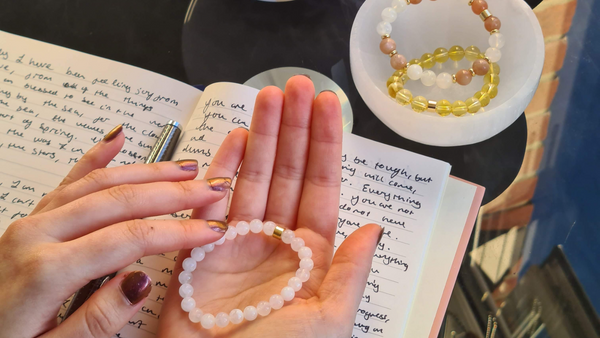 Manifesting and setting intentions with your Samayla jewellery. In the image a bracelet is held on the palm over a journal with writing on the pages.