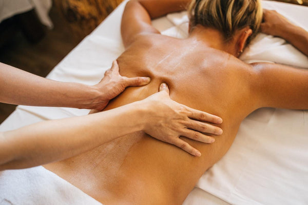 A woman laying face down receiving a massage for her back pain