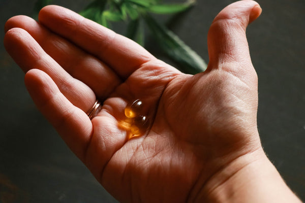 A hand holding CBD softgels