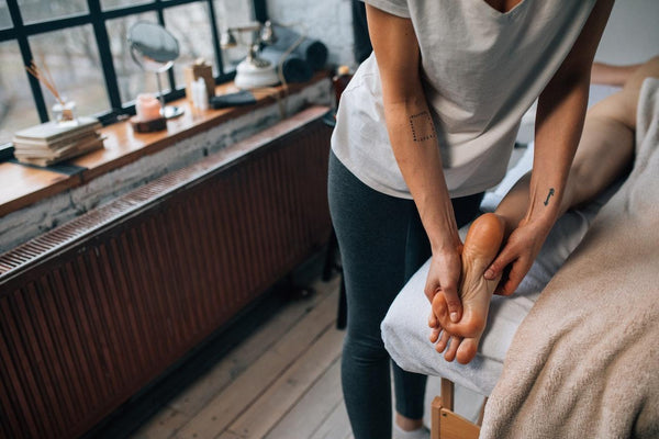 a paint therapist massaging the sole of a woman's foot with CBD