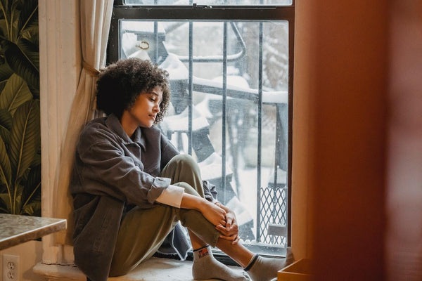 An anxious woman sitting down at the edge of her bed