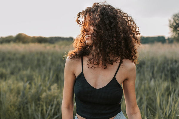 A woman with curly hair smiling outside