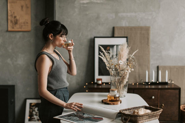 A woman standing in the kitchen drinking tea