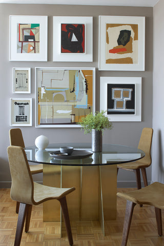 Dining room with table, chairs, and a back wall filled with art